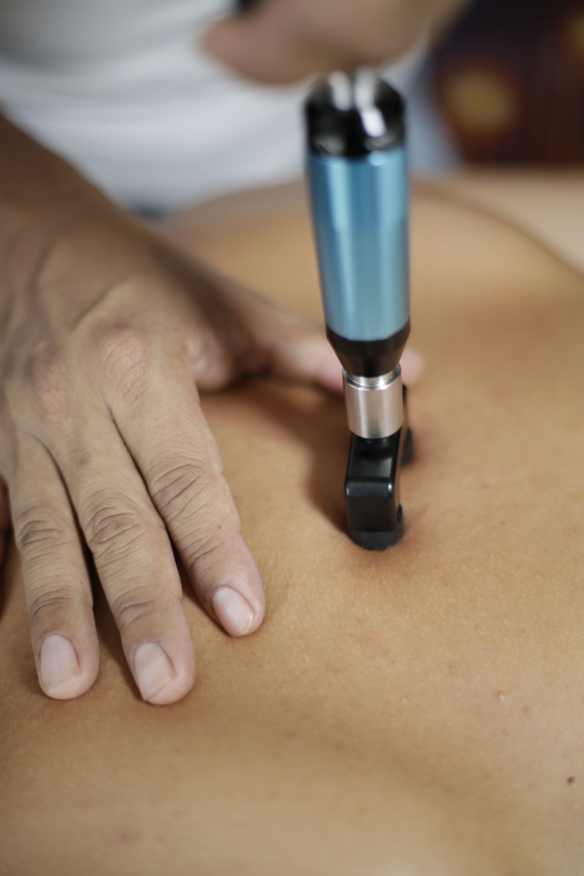 Therapist using a handheld device on a patient's back during treatment