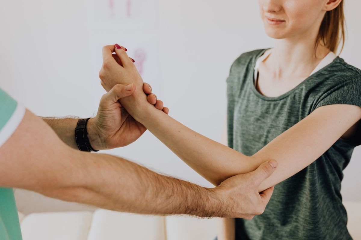 Chiropractor examining a smiling patient's arm during a session