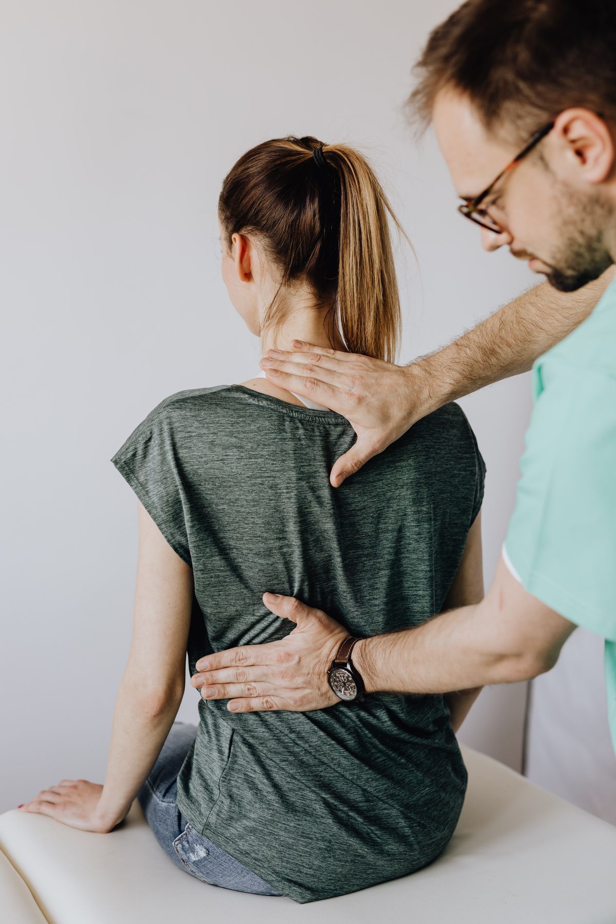 Chiropractor applying manual pressure to a patient's upper back and neck