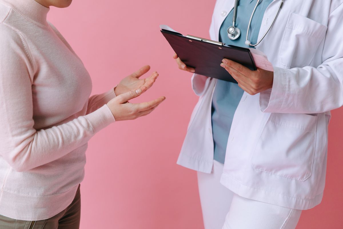 Patient gesturing while talking with a clinician holding a clipboard