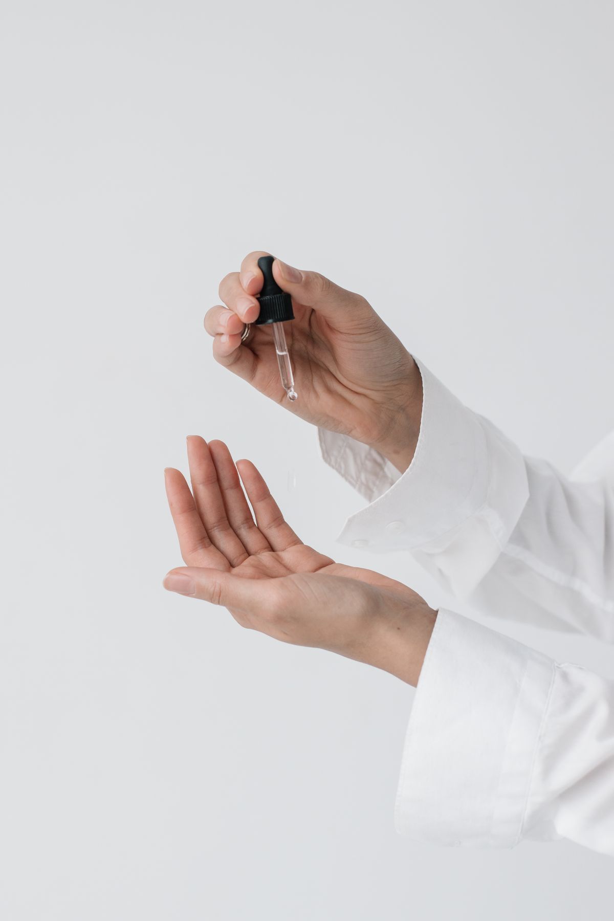 Close-up of hands applying serum with a dropper