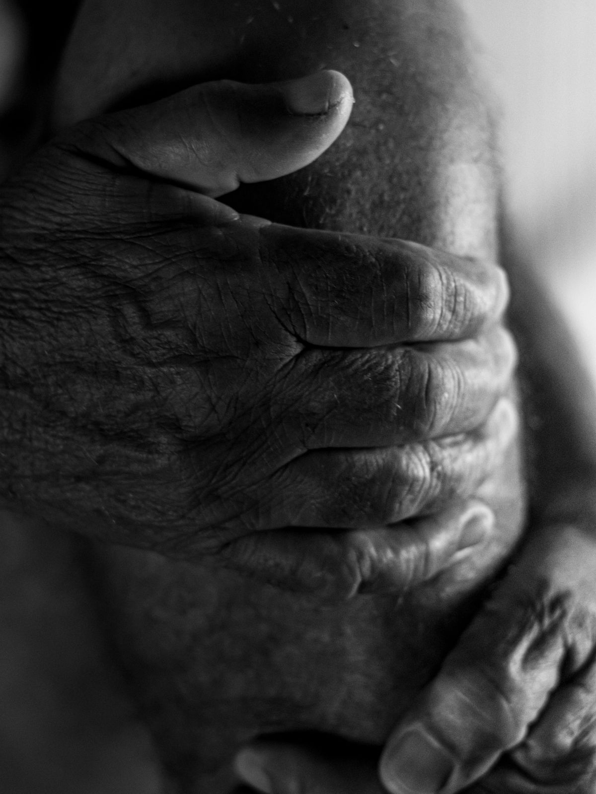 Close-up of an older person's hands resting on their knee