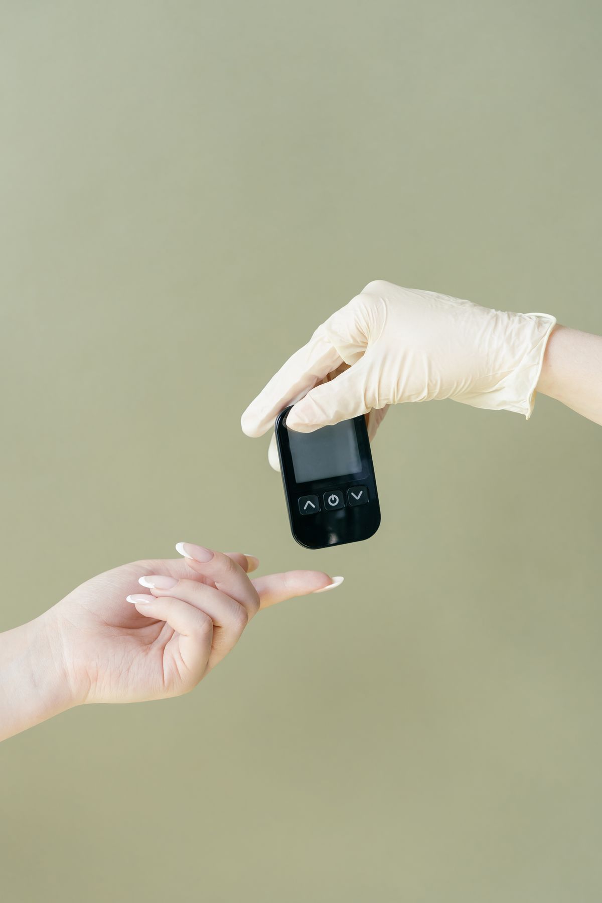 Gloved hand holding a glucose meter above an open palm