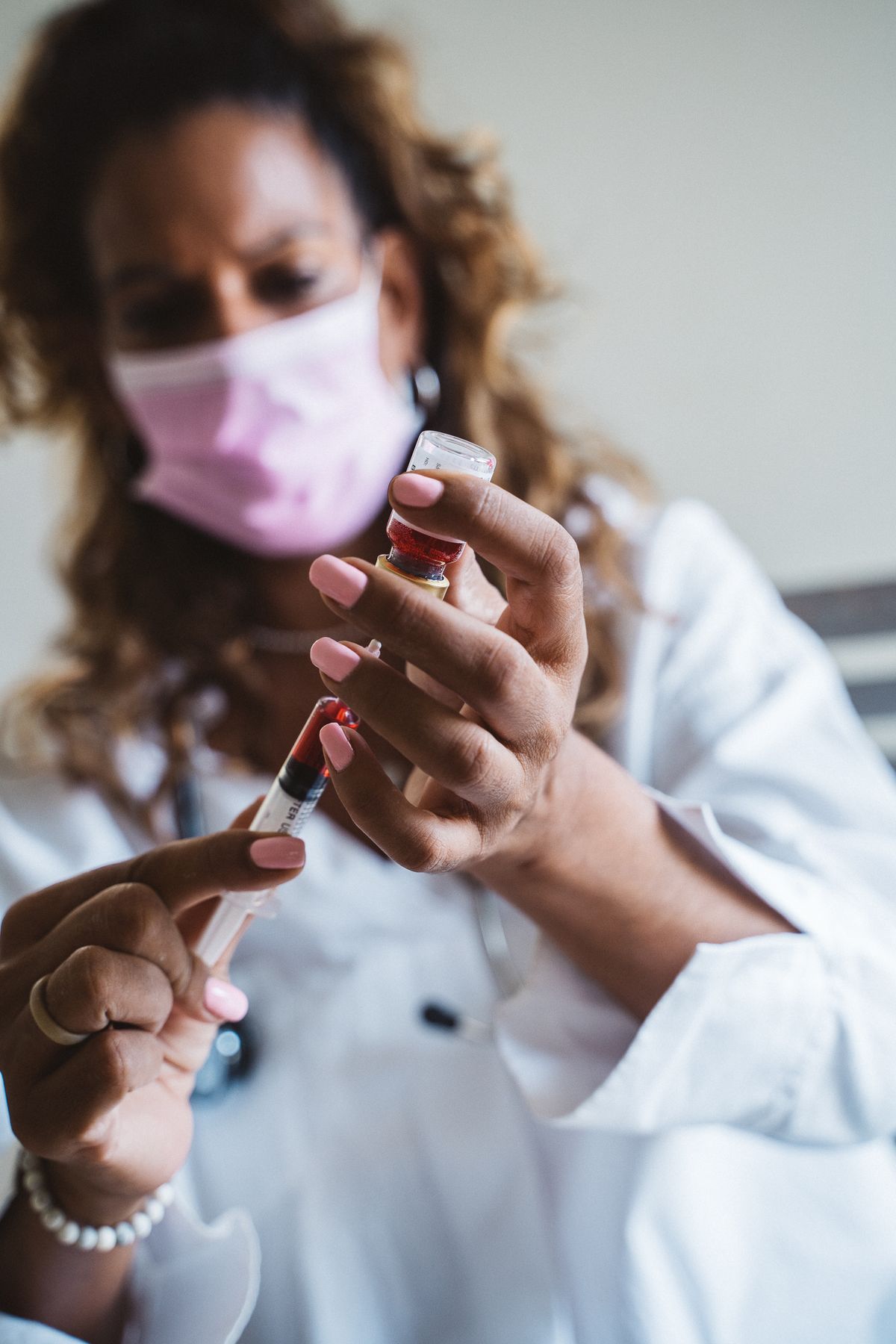 Gloved hand holding a syringe and a small vial