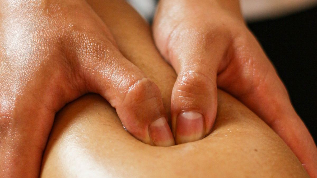 Close-up of hands pressing into a client's leg during a massage