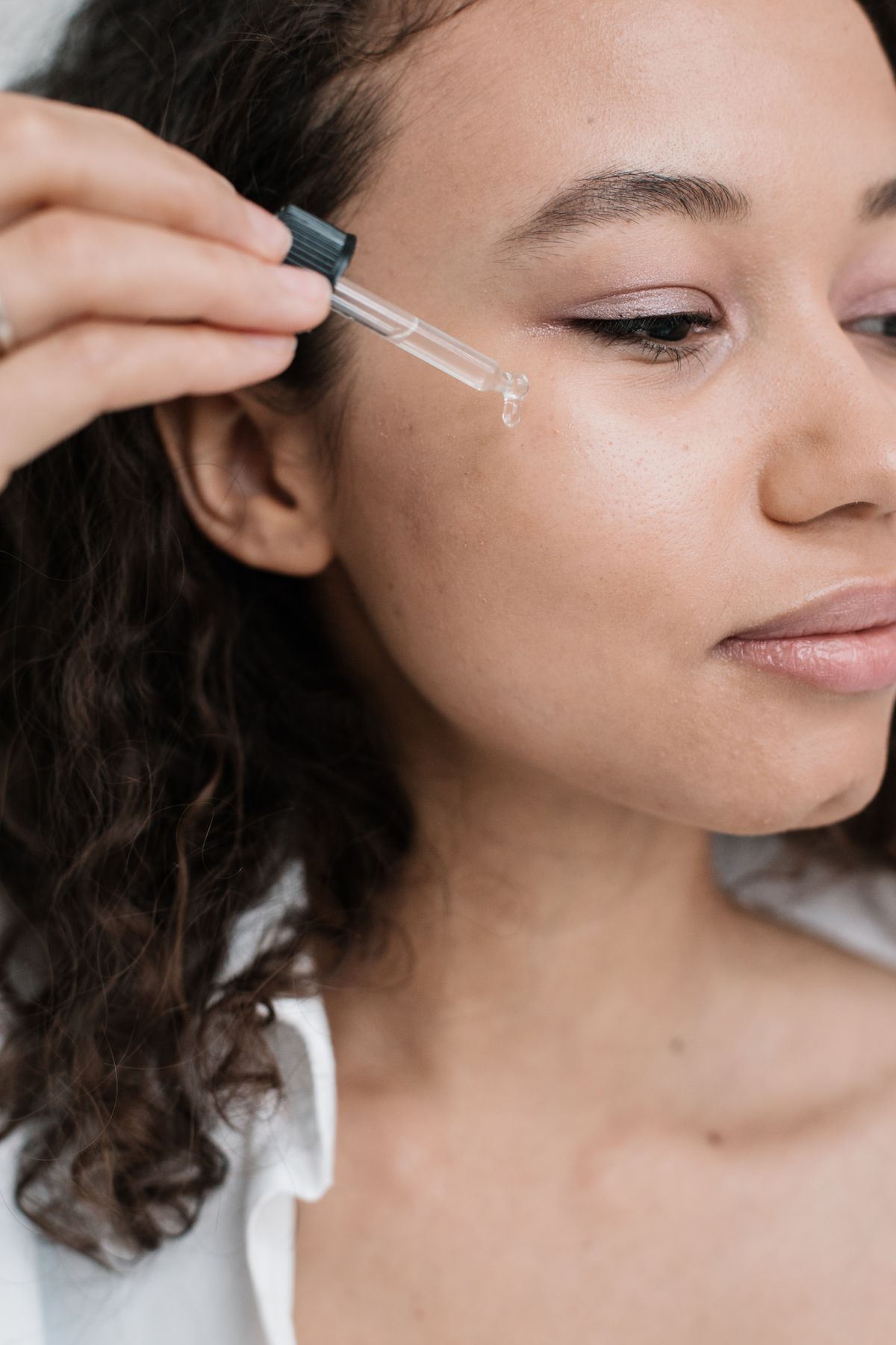Dropper applying serum to a woman's cheek
