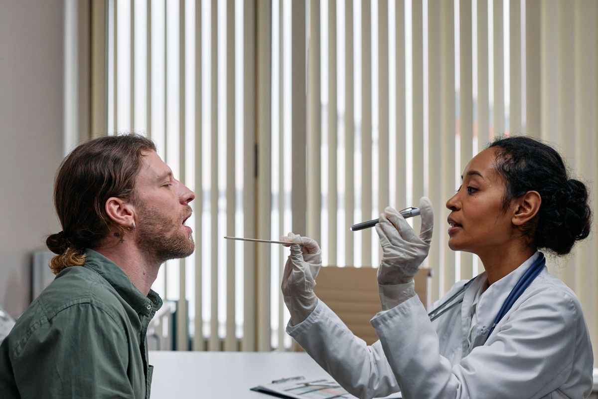 Doctor examining a patient's throat with a tongue depressor